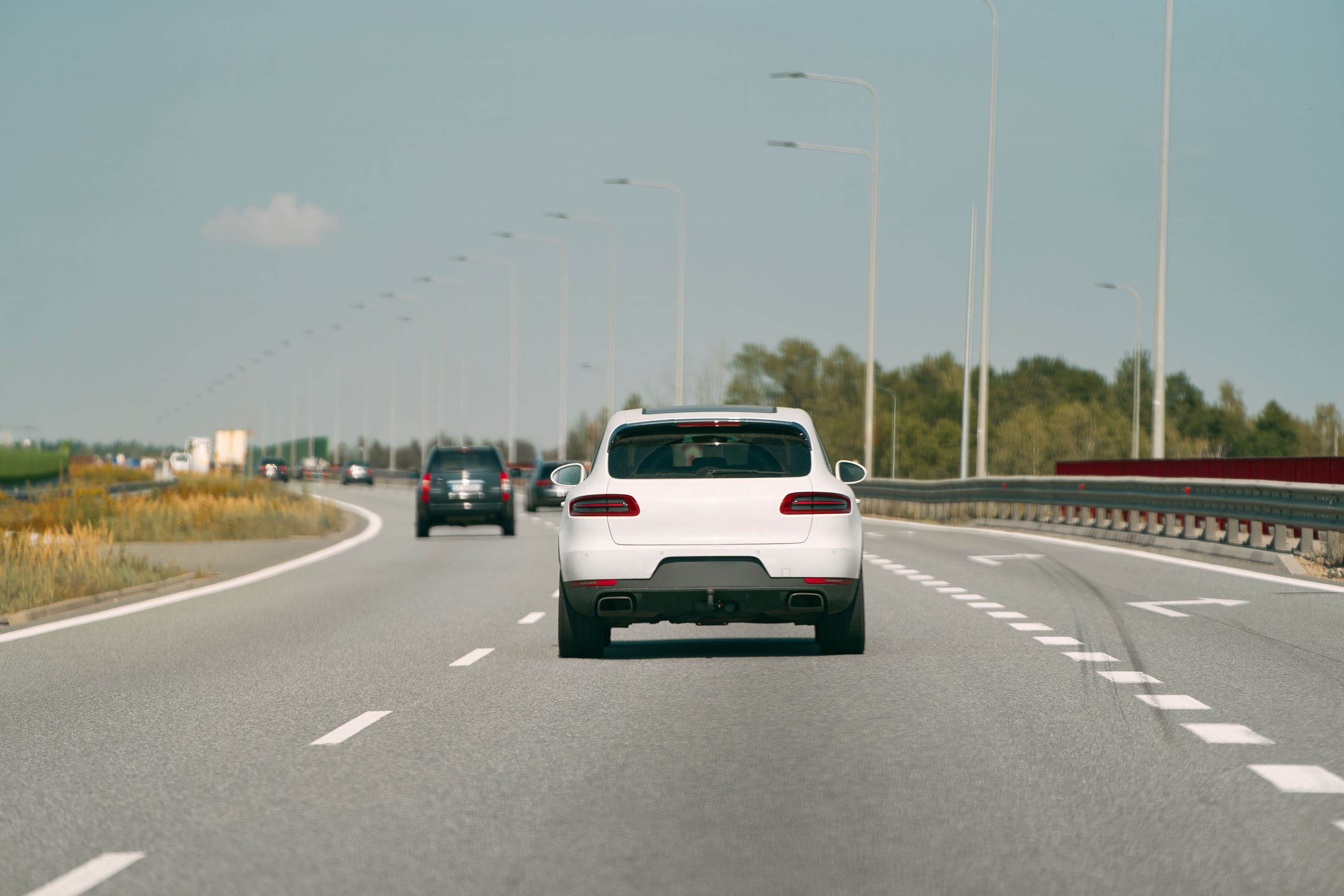 White car traveling down an open road.