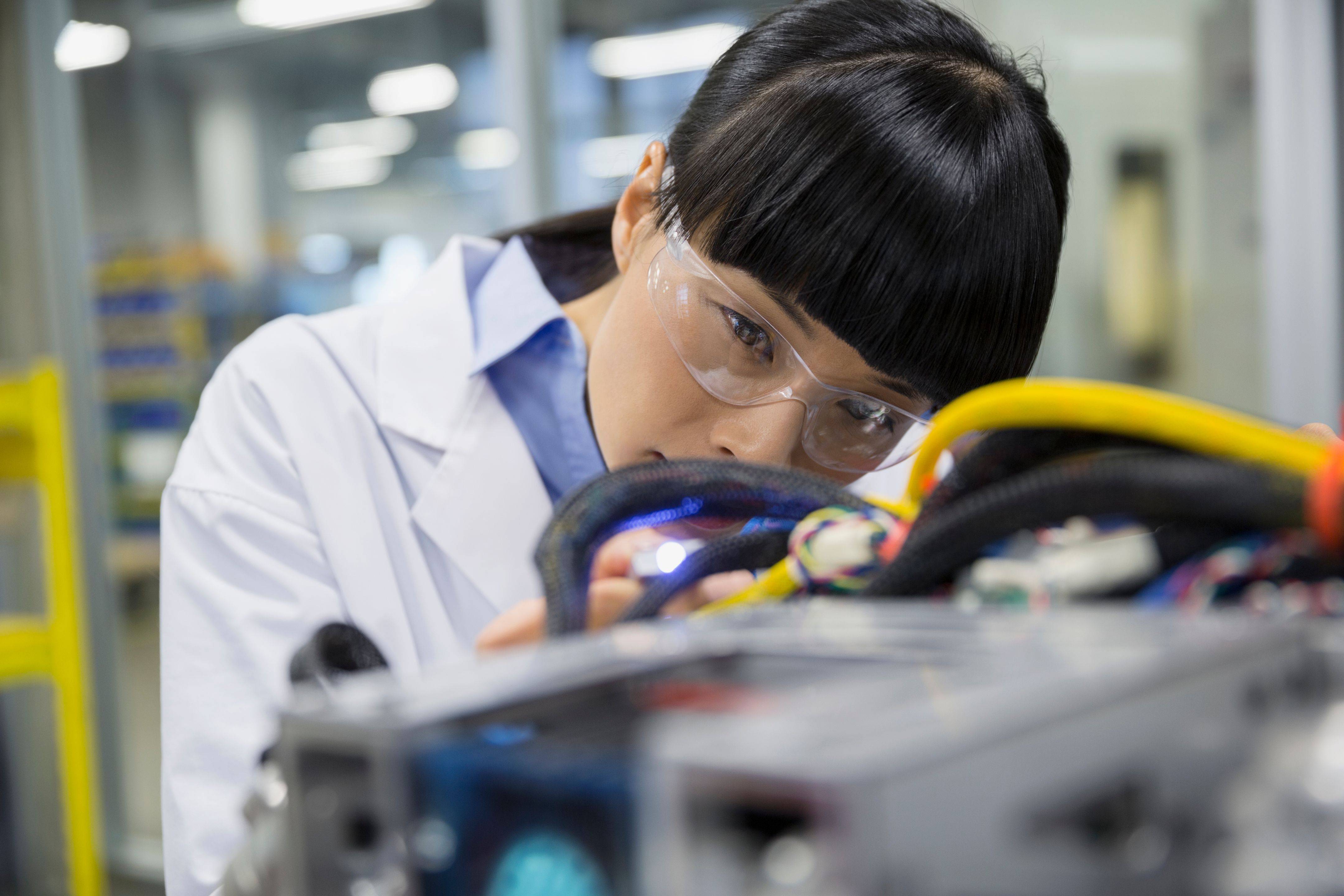 A focused female engineer examining robotics