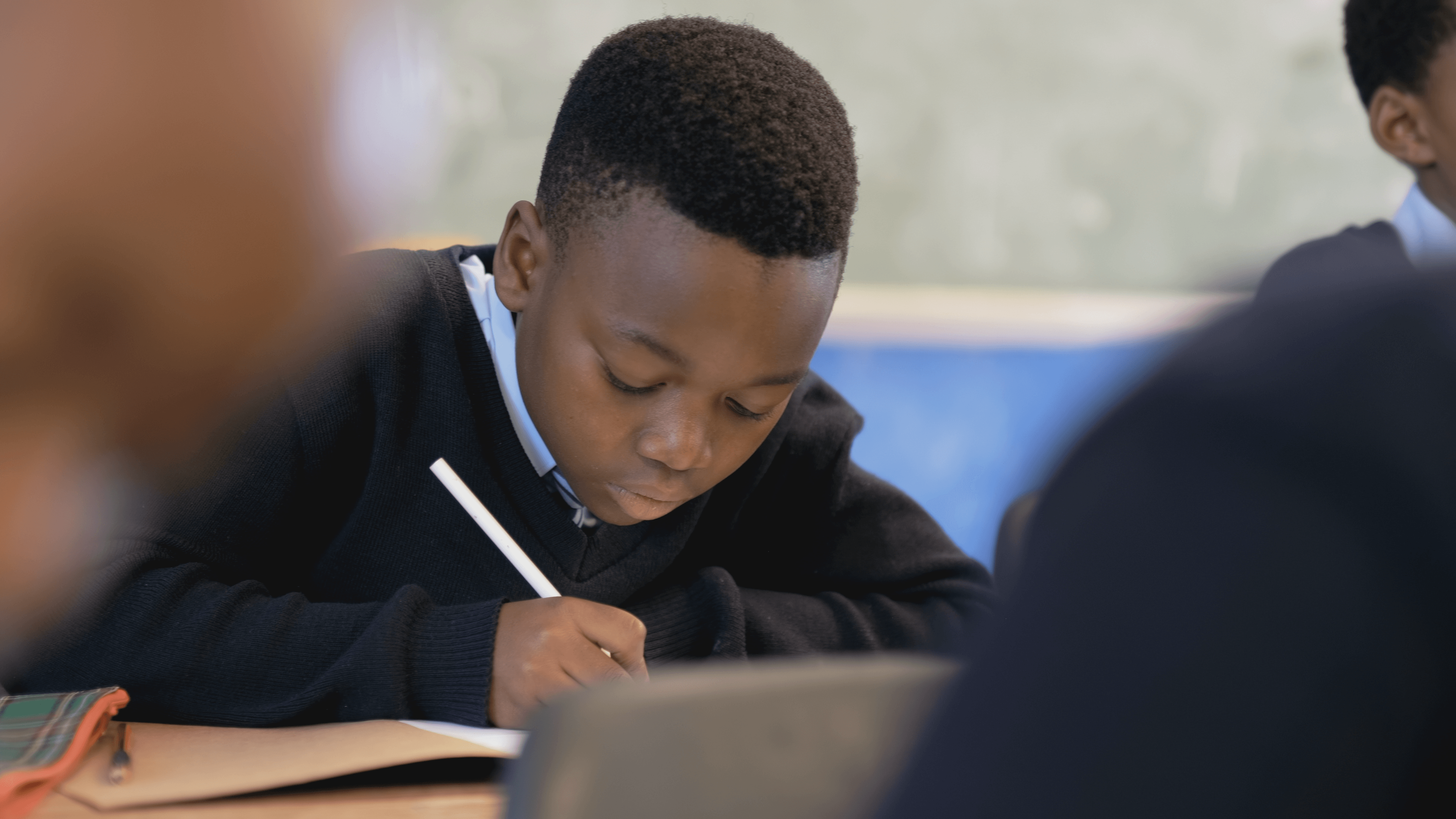 A student writing in a notebook in a City of Springfield classroom.
