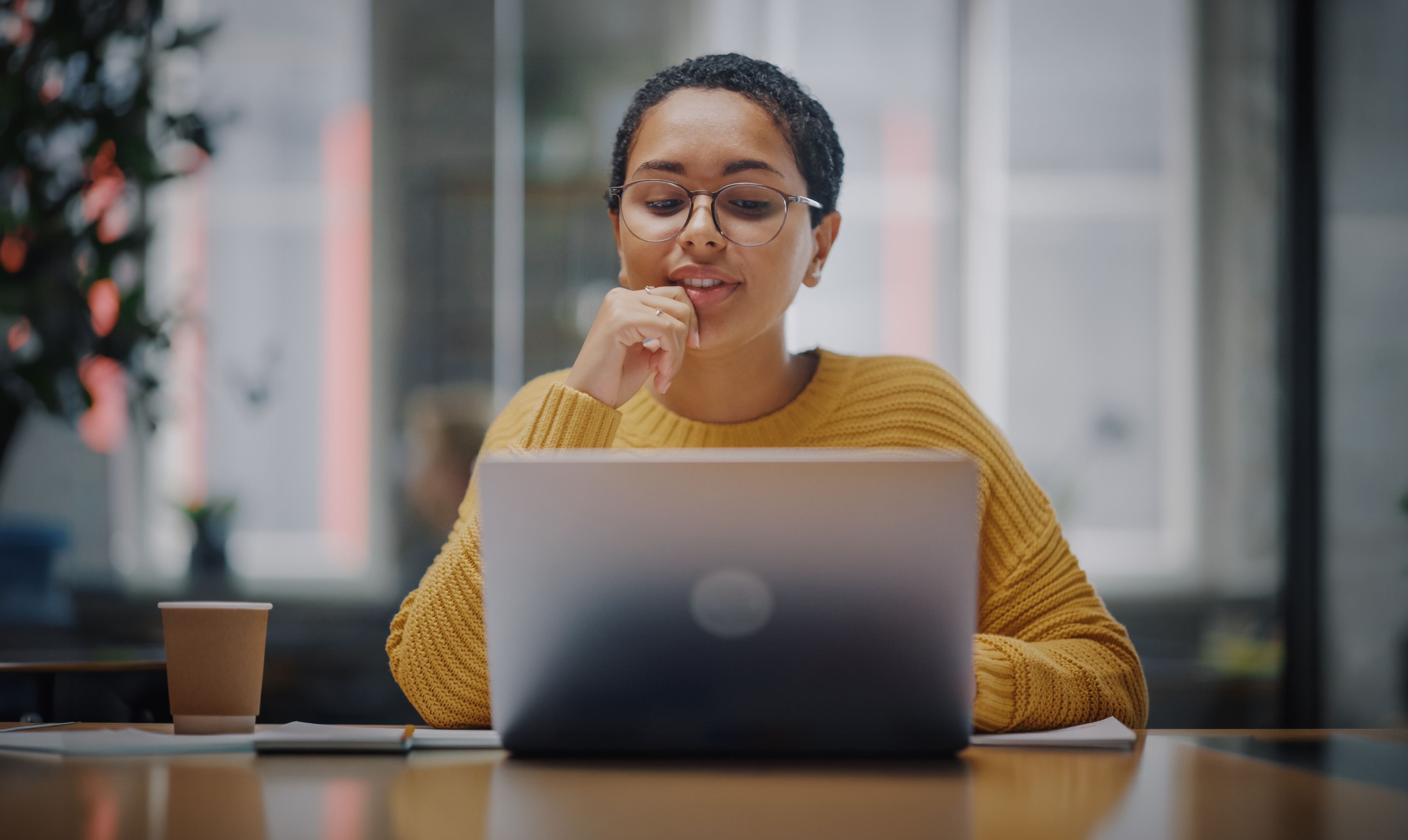 Een onderzoeker zit aan een bureau en werkt bedachtzaam op een laptop