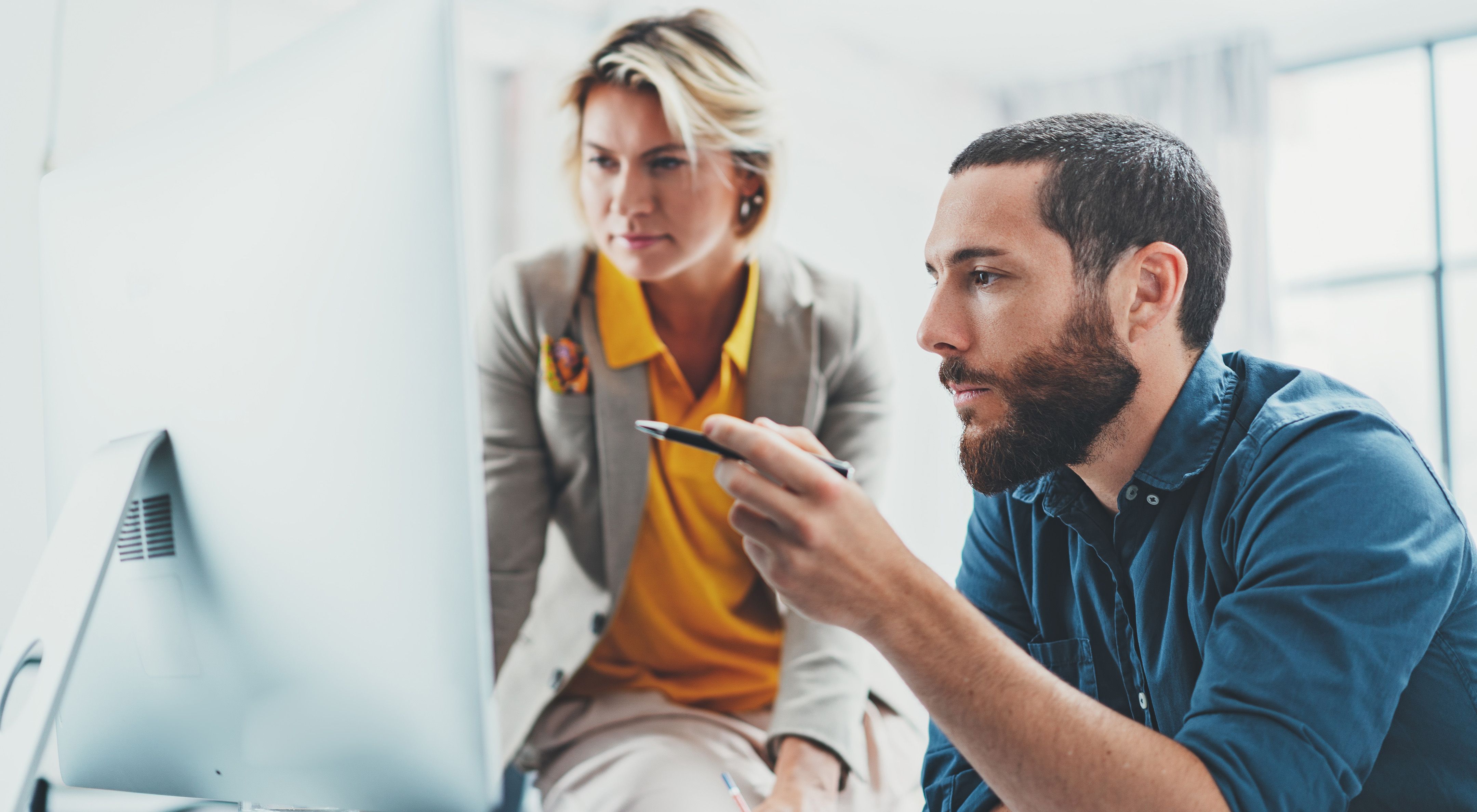 A female corporate leader looks at a computer screen with a colleague