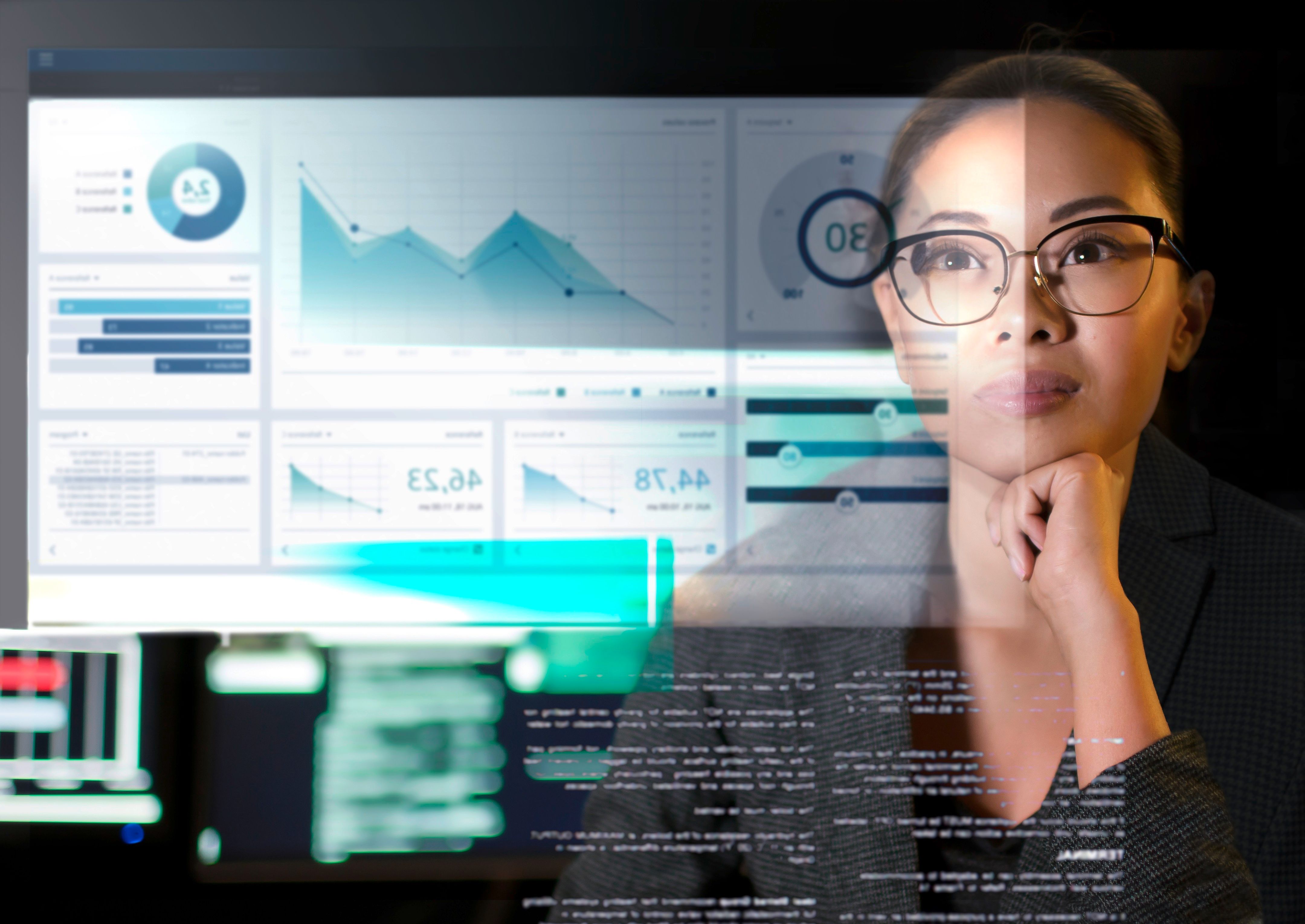 Person analyzes layered dashboards, charts, and code on transparent digital screens in a tech environment