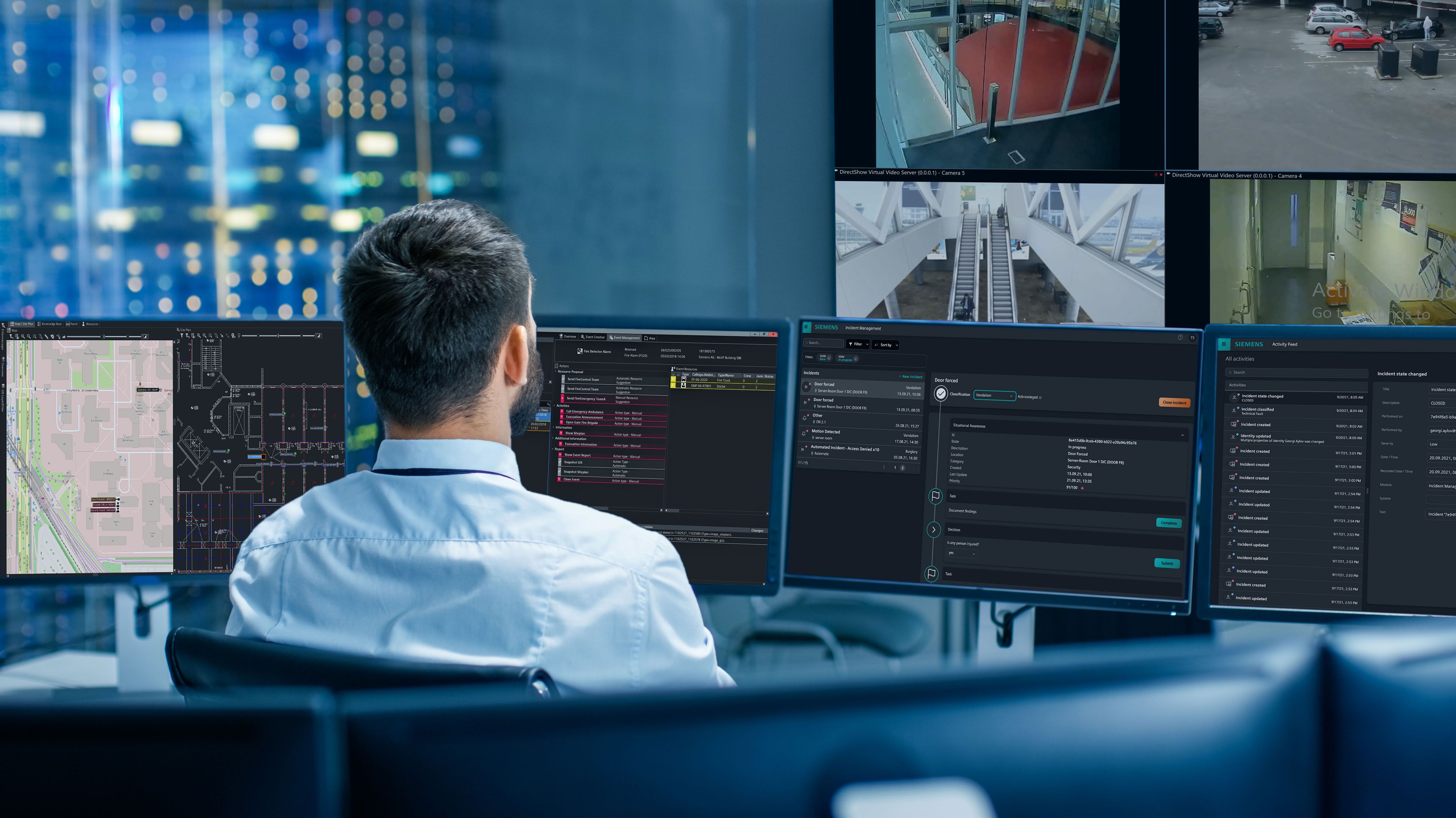 En kontrolrumsoperatør overvåger Siemens dashboards, kort og live overvågningsfeeds på tværs af flere skærme.