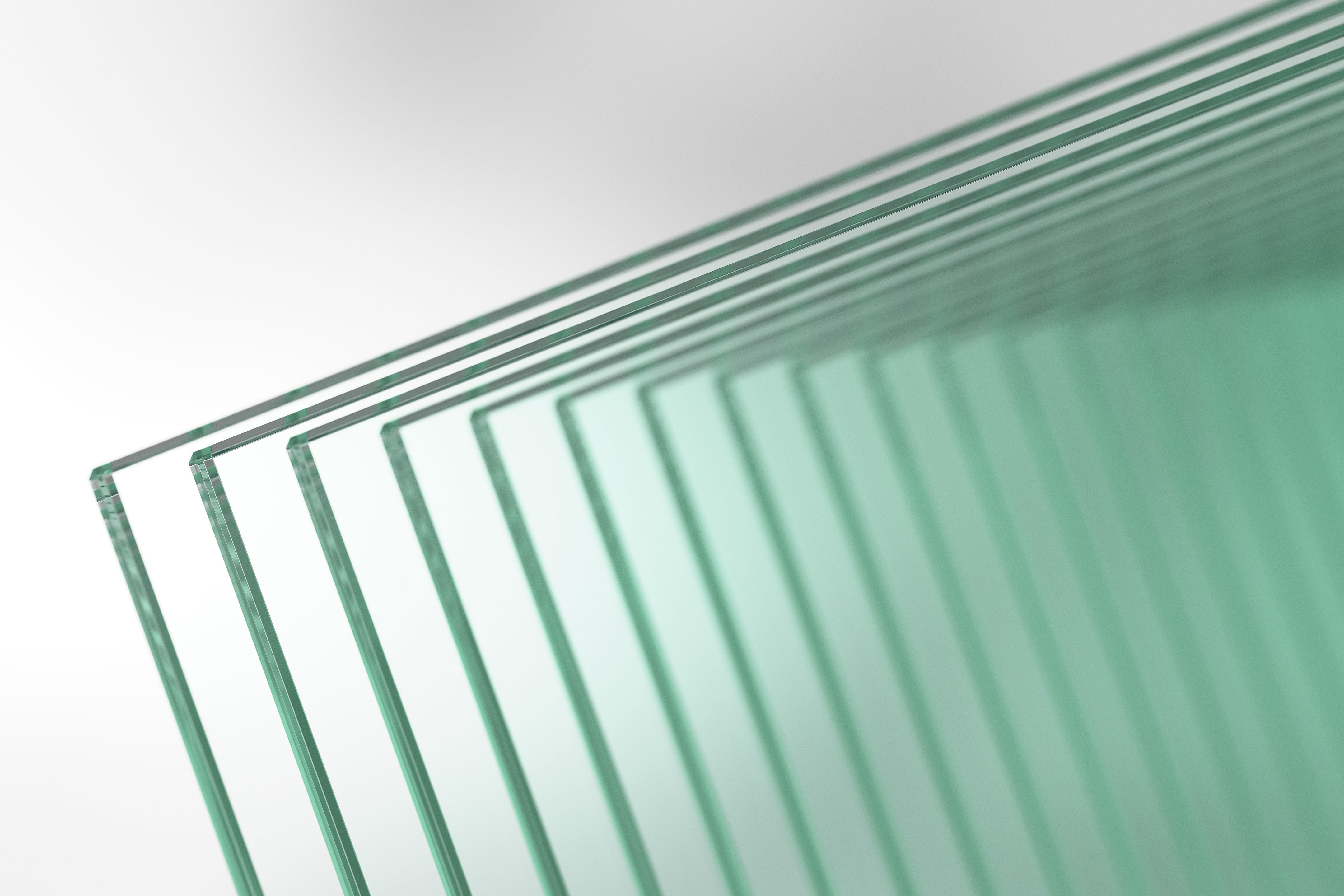 Stack of thin green-tinted glass sheets aligned diagonally with shallow depth of field.