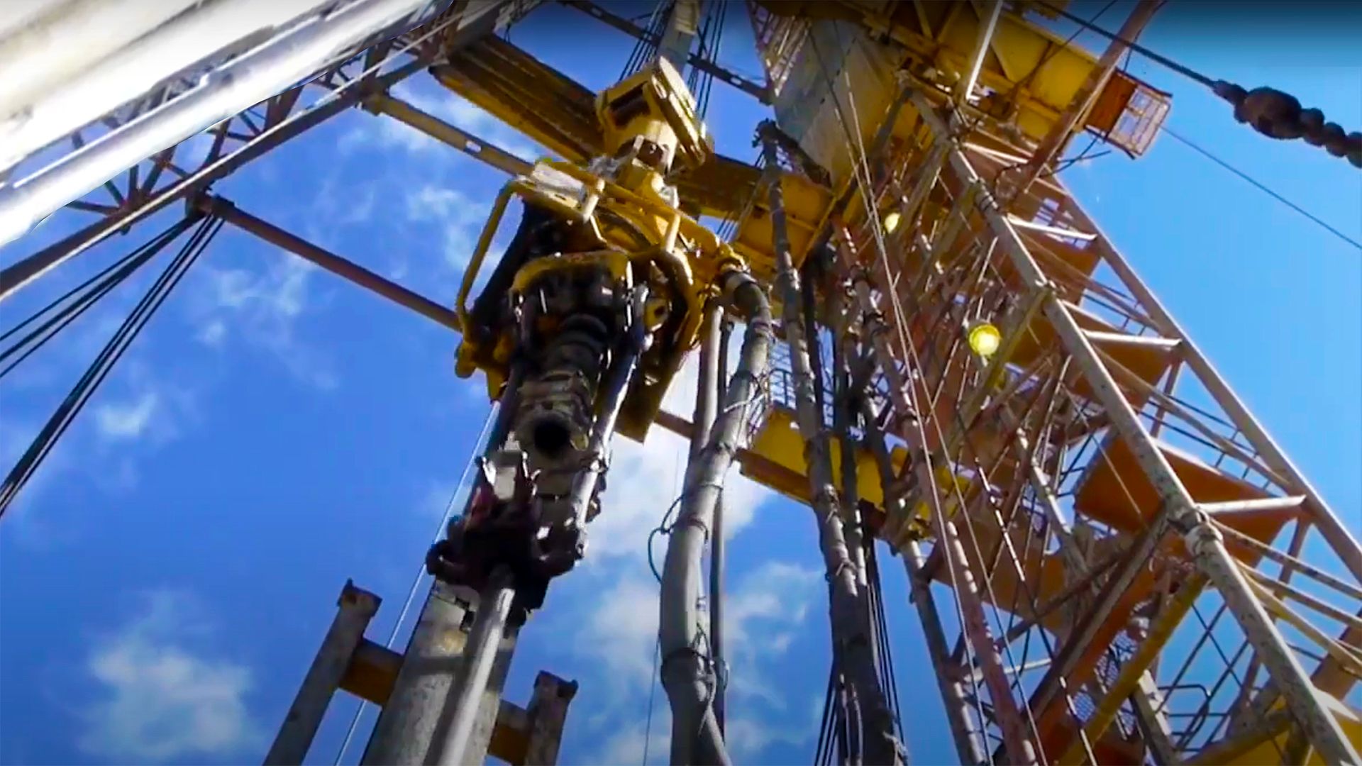 Oil drilling rig with automated pipe-handling equipment performing drilling operations at an industrial energy site
