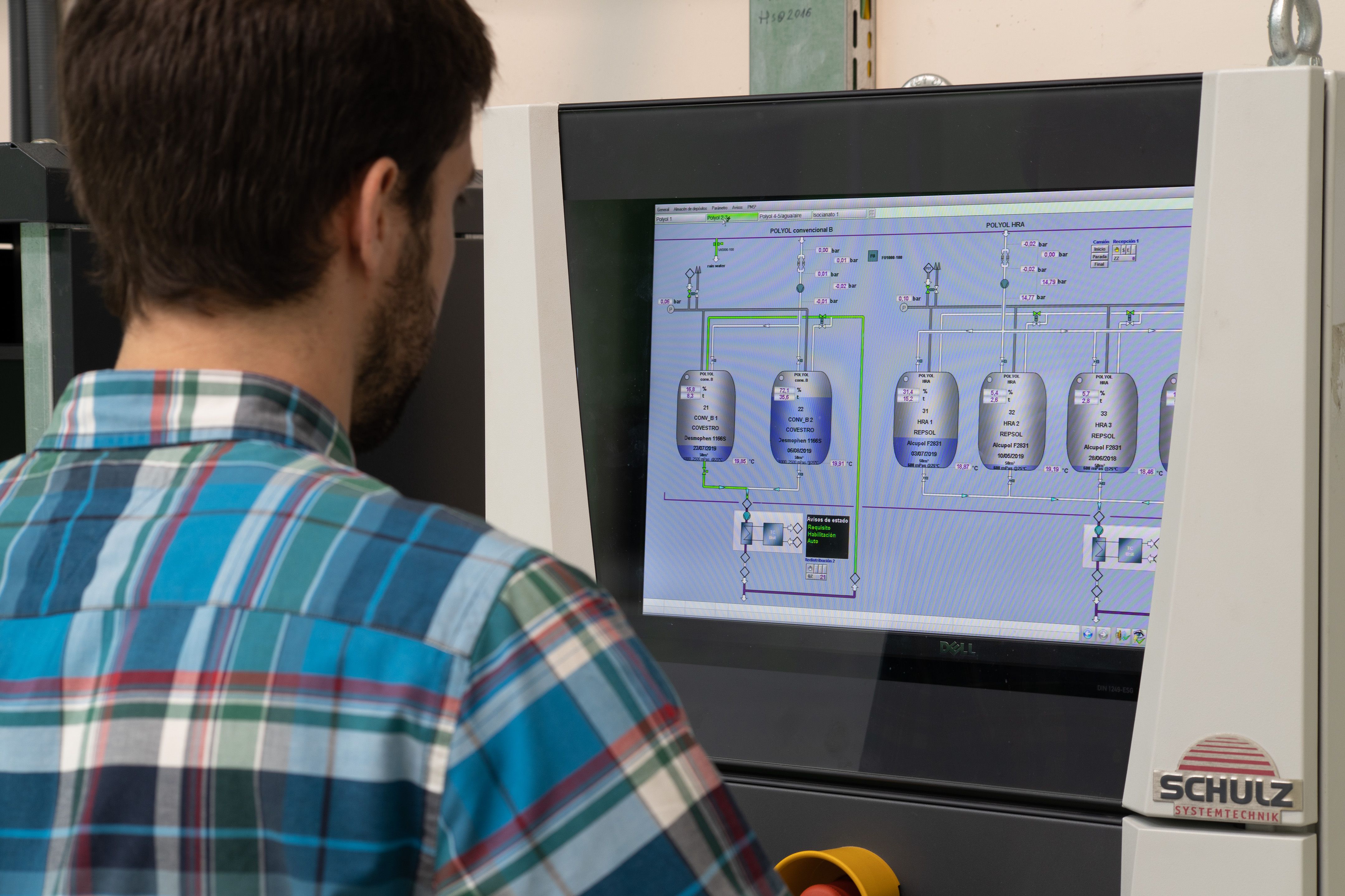 A man, who is looking at a screen showing an application and data, is seen from behind.