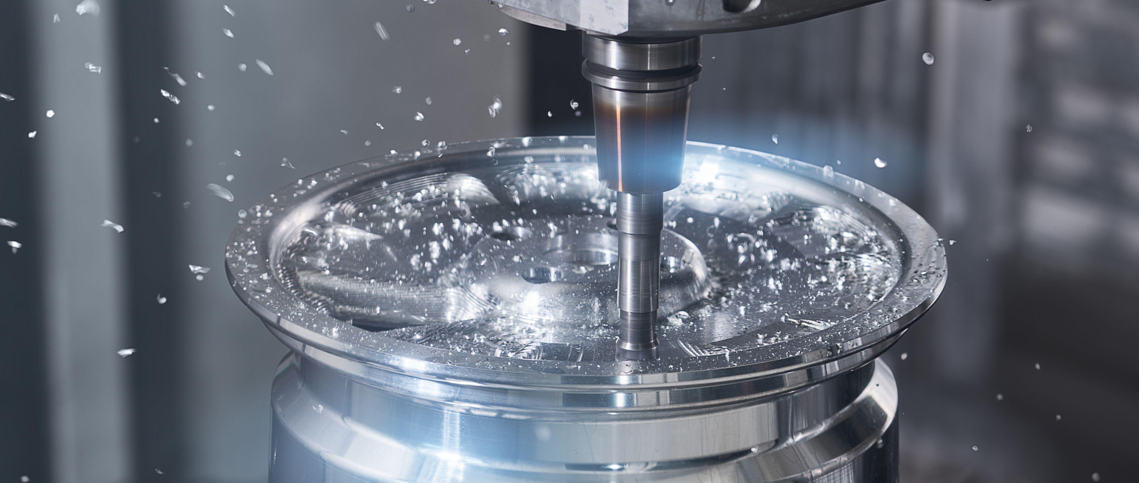 CNC milling machine cutting a circular metal workpiece, with metal chips and coolant spray flying during high-speed machining