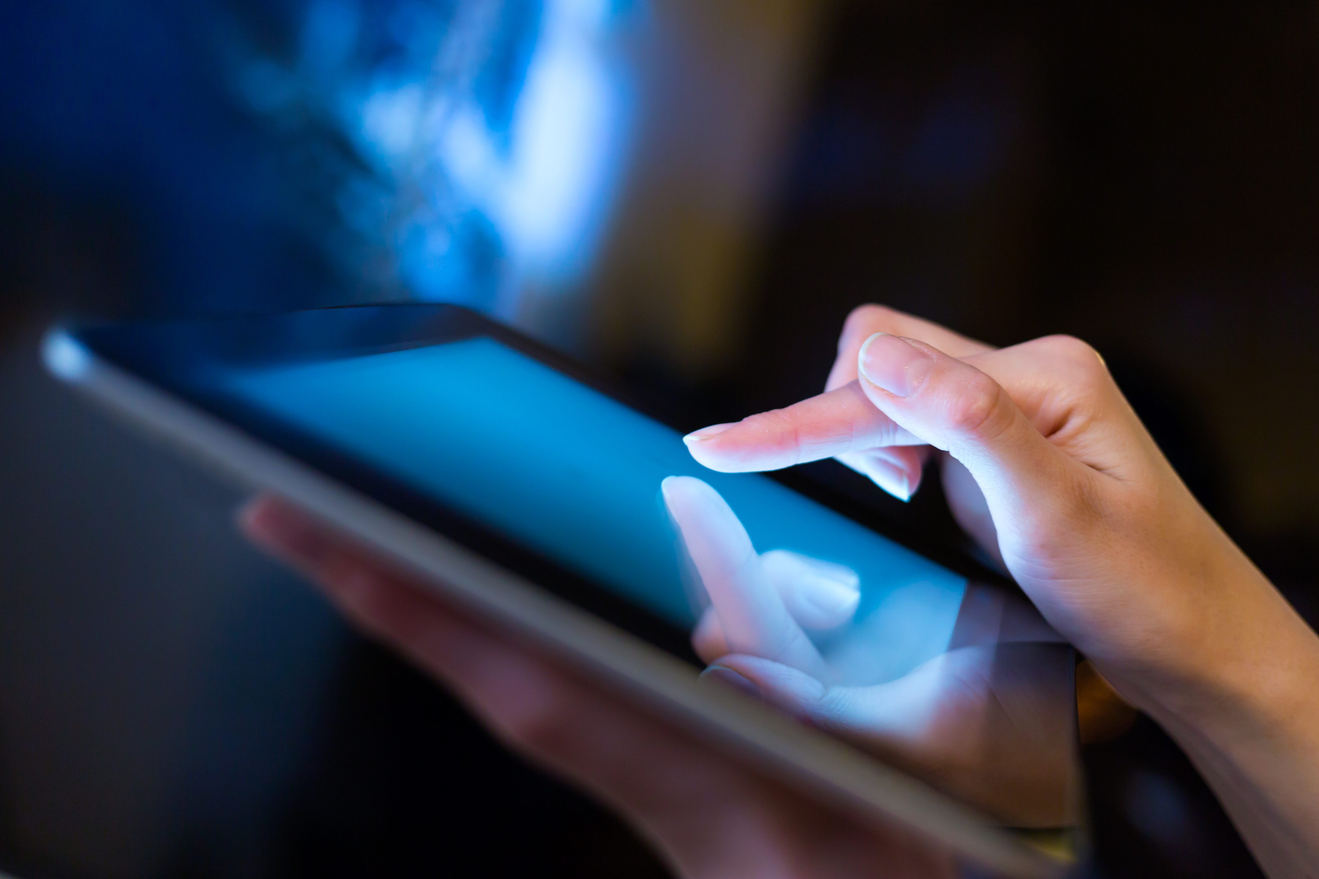 Les mains tiennent une tablette et l'utilisent.