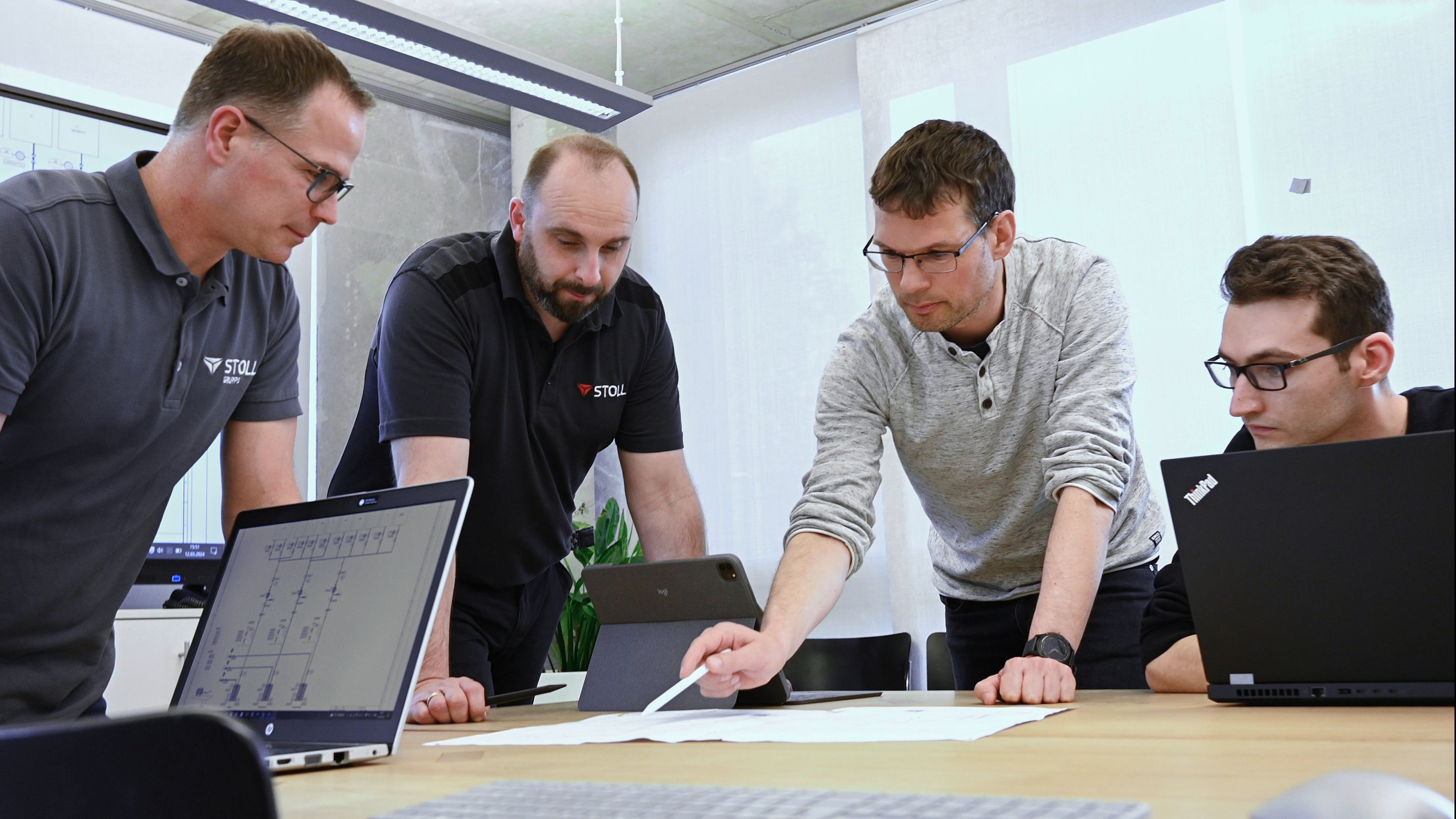Team that handled the development of the customer-specific equipment module sitting around a desk in a meeting room.