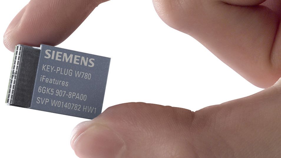 Ruka držící výměnné paměťové médium Siemens PLUG pro uchování konfigurace zařízení SCALANCE
