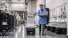 A man with a laptop walking beside an automated guided vehicle on a next-generation factory floor.