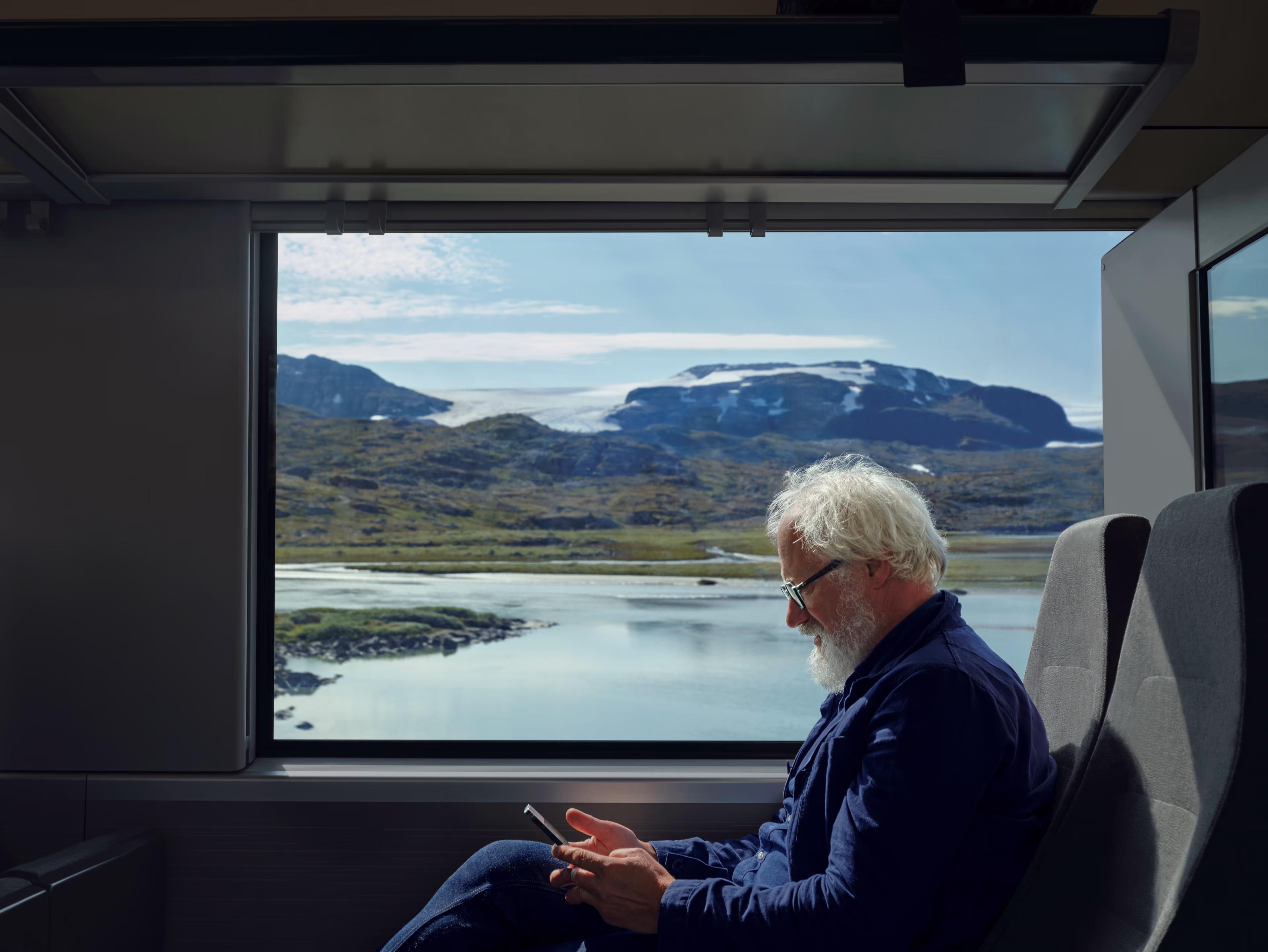 Train passenger with scenic mountain lake through large window