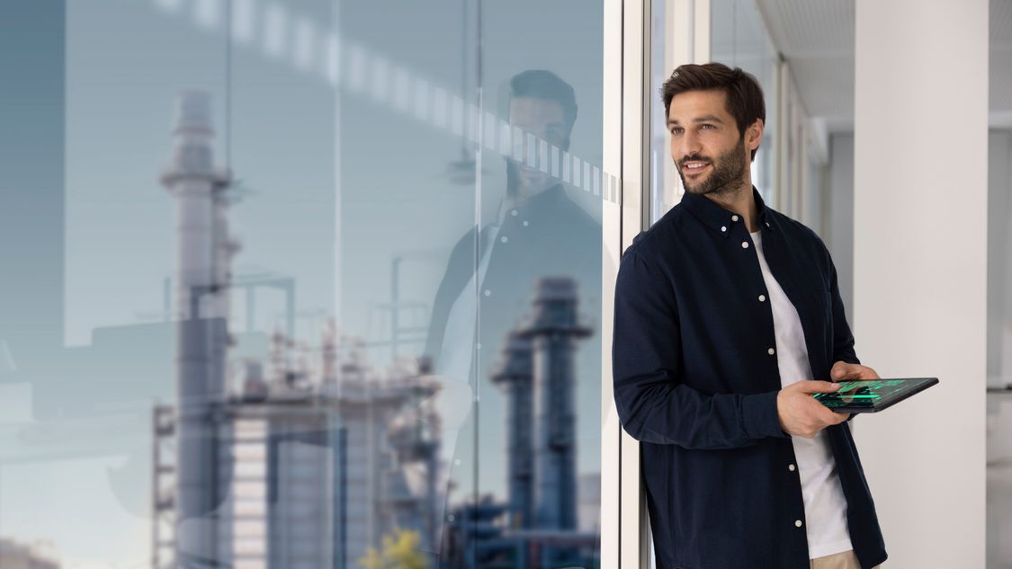 In a futuristic-looking, not clearly defined background in dark colors, the face of a good-looking man in his mid-twenties, looking forward - not into the camera but rather at a stylized globe that also has a digital appearance. The man's face expresses interest, determination and intelligence. 