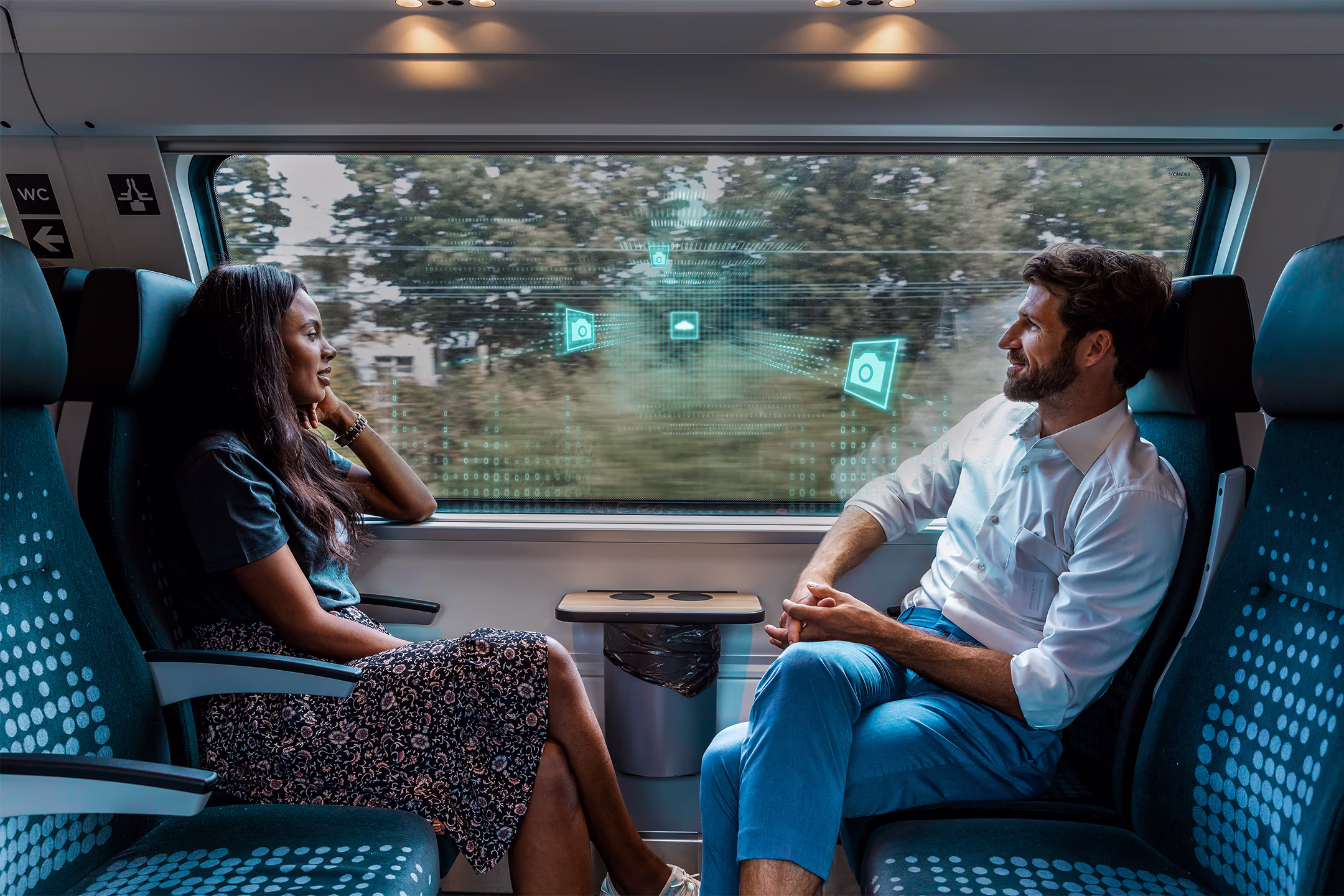 Zwei Fahrgäste sitzen in einem Zugabteil nebeneinander und schauen aus dem Fenster. Im Fenster sind digitalisierte Icons zu sehen. Intelligente Videoüberwachung