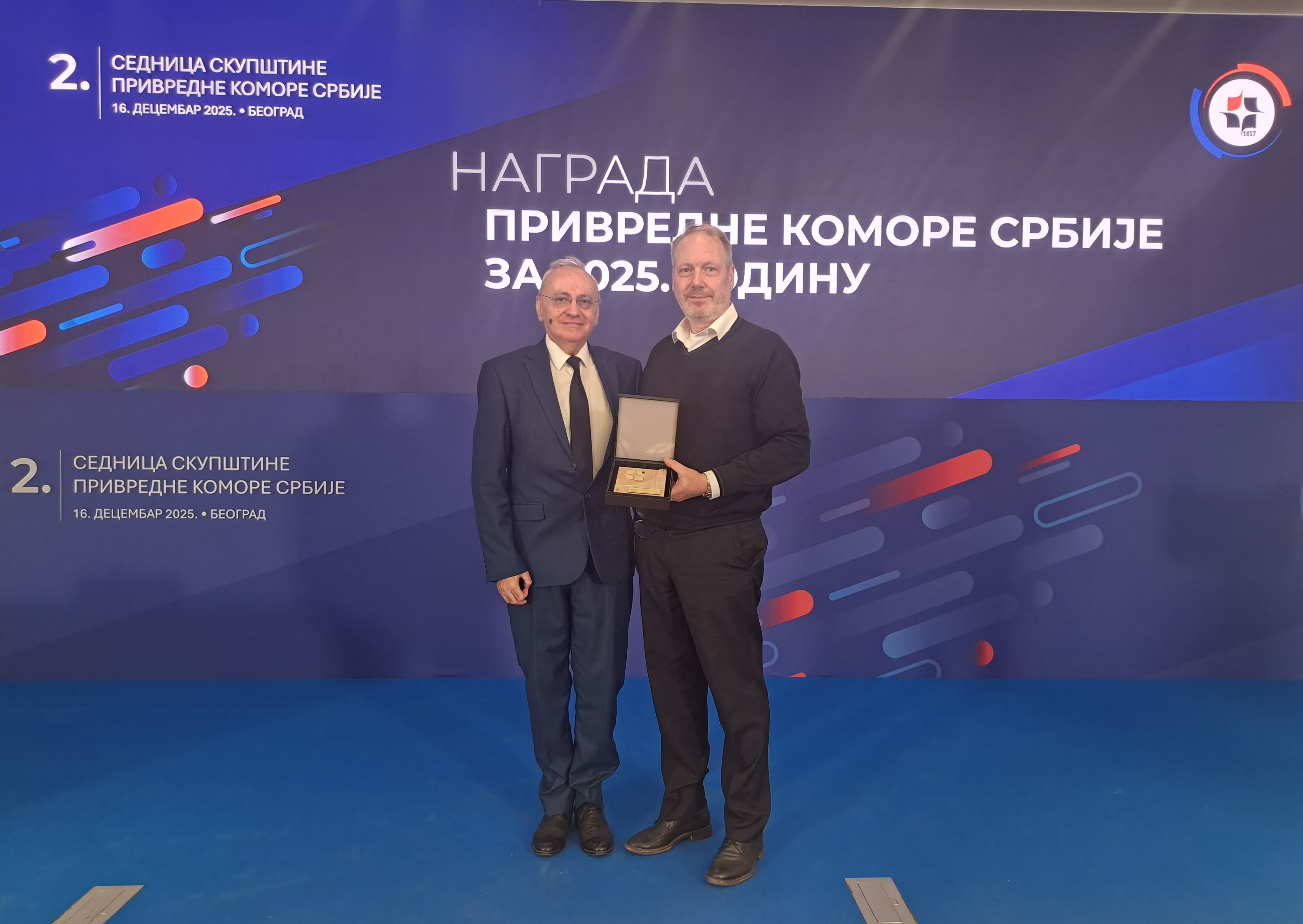 Two men at Serbian business award ceremony, one holding plaque Two men at Serbian business award ceremony, one holding plaque