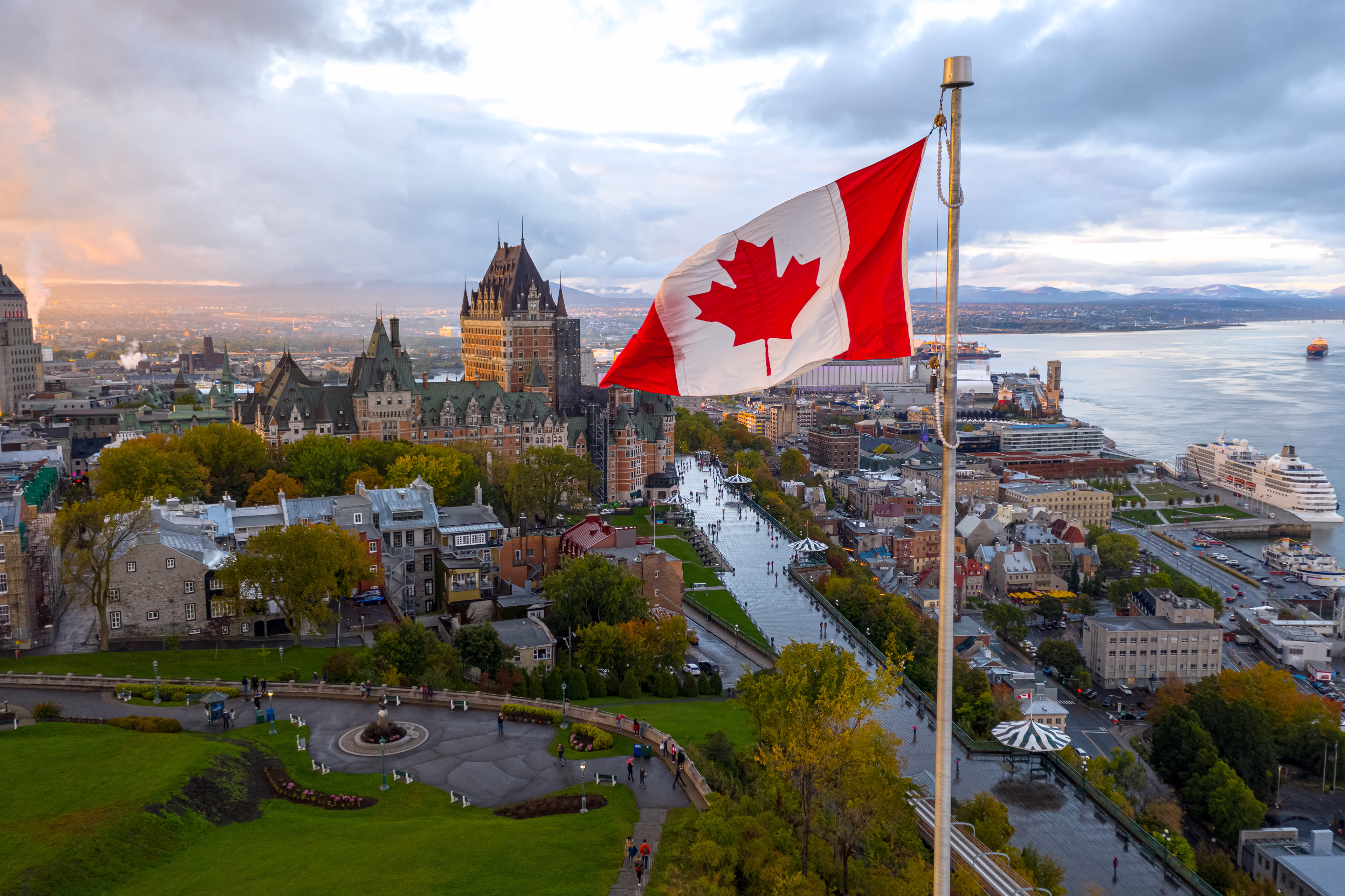 Drapeau canadien flottant sur un mât de drapeau. Prise au coucher du soleil avec le Vieux Québec et le fleuve Saint-Laurent. drapeau-canadien-flottant