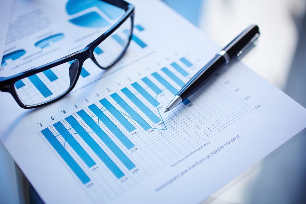 ett par glasögon och en penna och en rapport som visar finansiella diagram