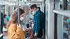 Zwei Passagiere mit Masken an Bord eines Zuges umgeben von Lösungen zur Risikominderung während einer Pandemie