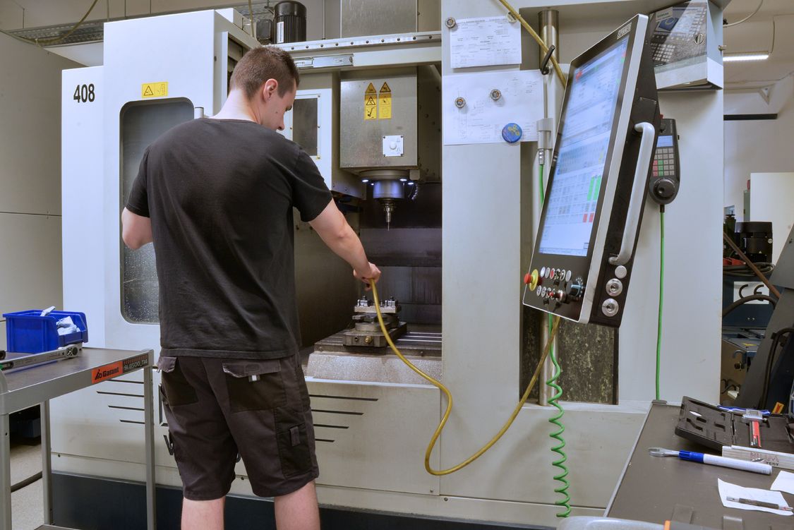 Foto des neuen Fertigungsleiters vor einer geöffneten Werkzeugmaschine mit Sinumerik-CNC