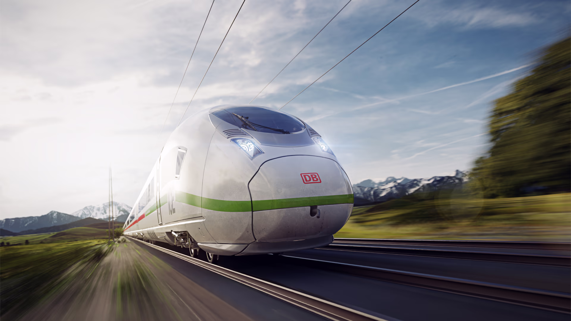Bild des Velaro MS von Siemens Mobility in leichter Diagonalansicht bei der Fahrt durch eine grüne Landschaft; im Hintergrund sind Berge zu erkenne. Siemens Mobility Hochgeschwindigkeitszug Velaro MS