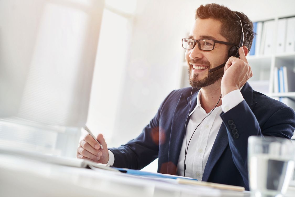 Smiling businessman using headset when talking to customer