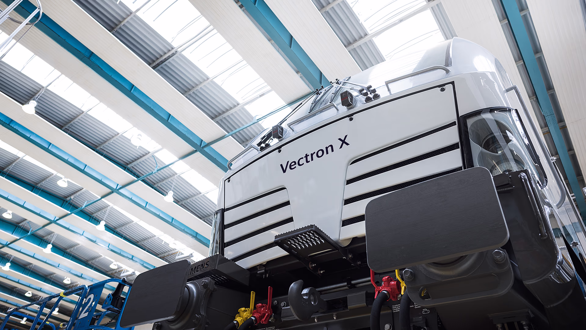 A front view of a Vectron X locomotive from a low angle. The locomotive is parked in a factory with bright overhead lighting. vectron-front