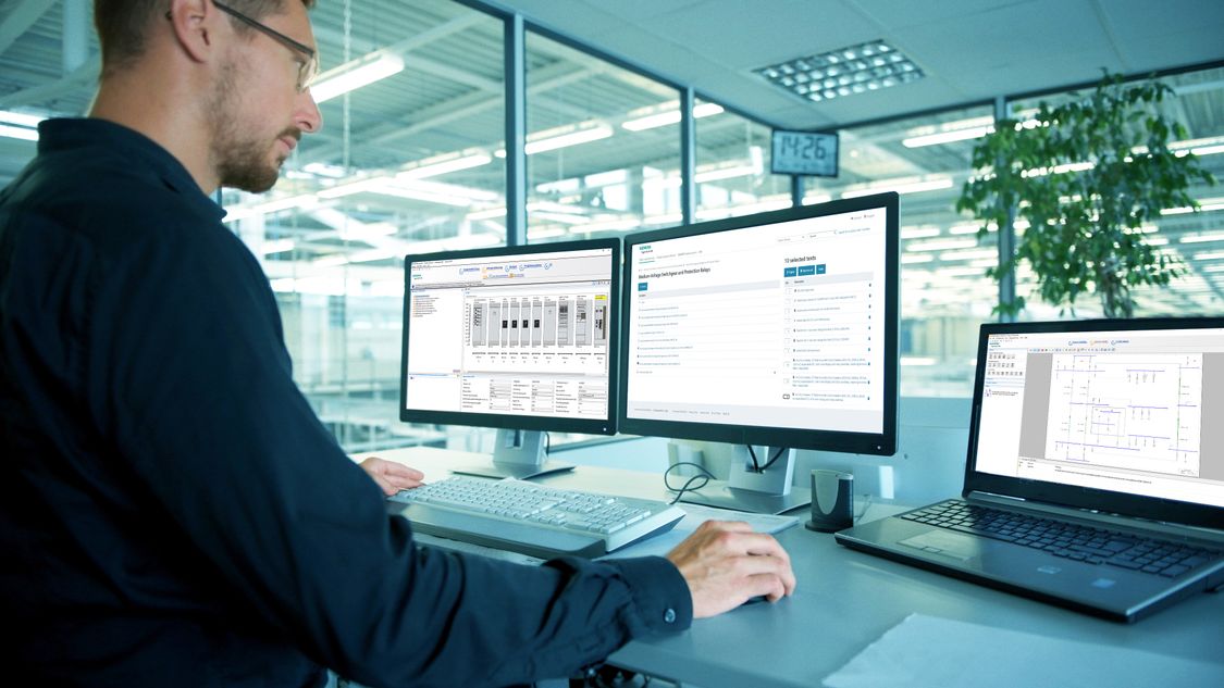 Man in front of double screen plus opened laptop