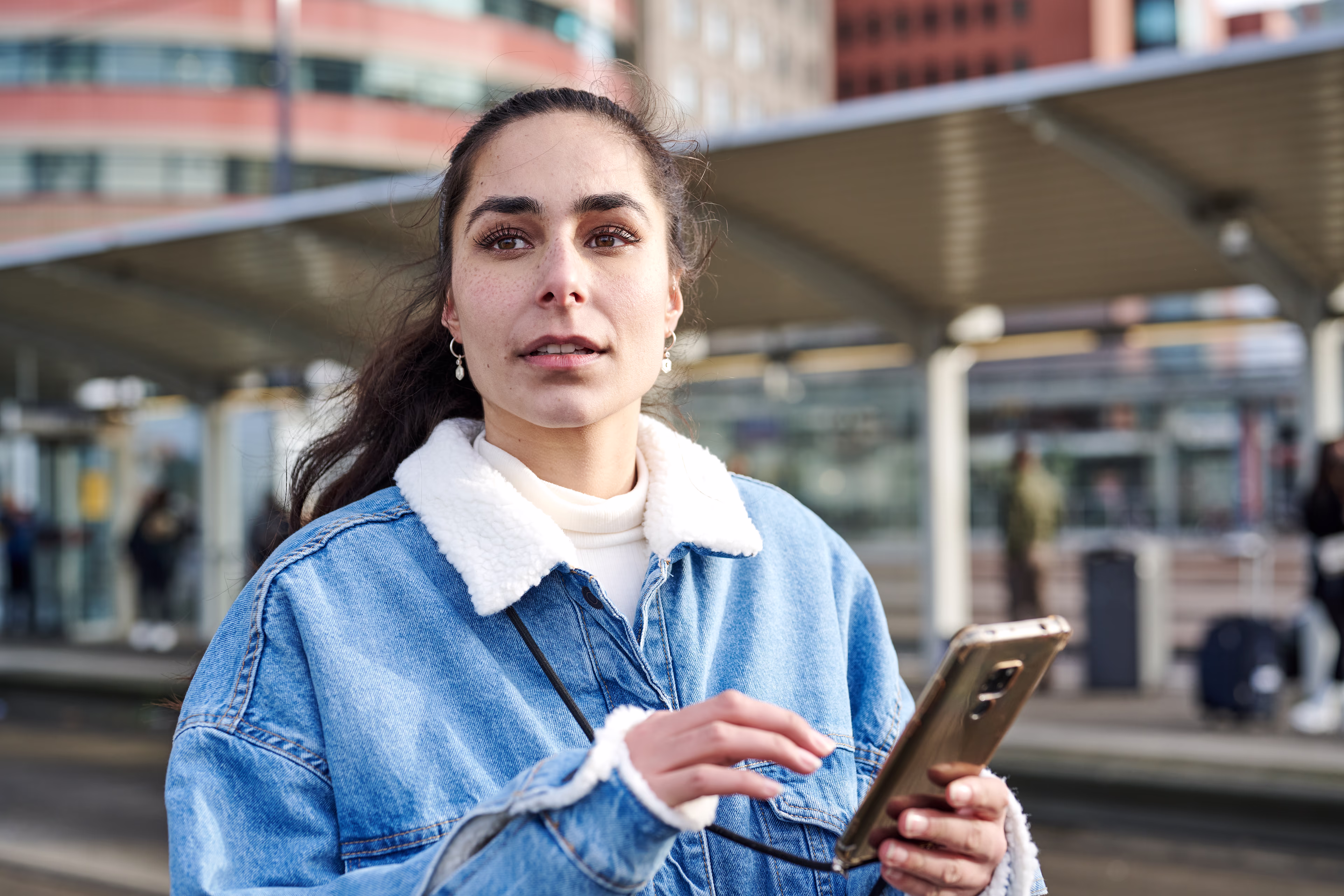 A young woman uses her smartphone to find out about travel options A young woman uses her smartphone to find out about travel options