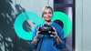 Woman holding VR headset, turquoise image of an infinity loop behind her Woman holding VR headset, turquoise image of an infinity loop behind her