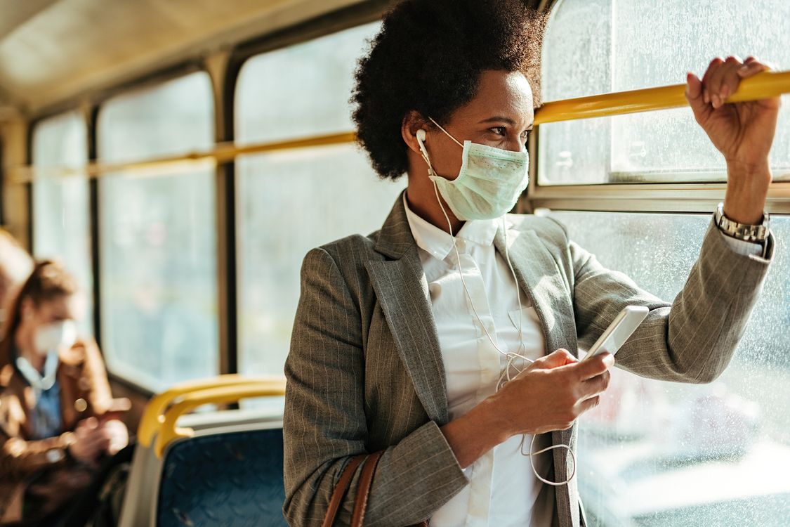 Photo of a women taking public transit with a mask on