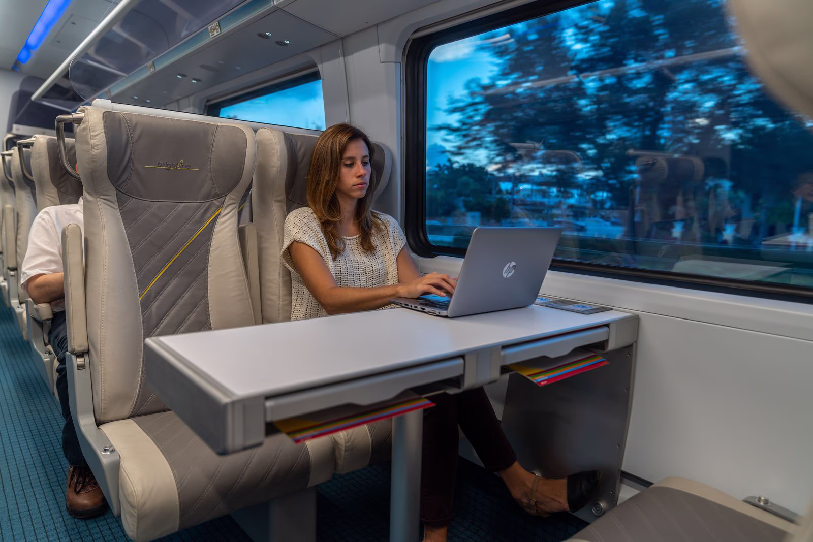 Women on laptop sitting on Brightline West Train Women on laptop sitting on Brightline West Train
