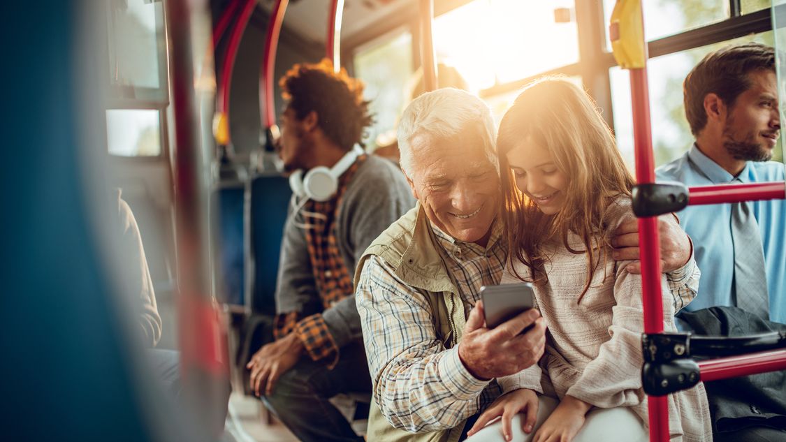 A grandparent and child on a bus enjoy an improved passenger experience thanks to intermodal travel apps and solutions 