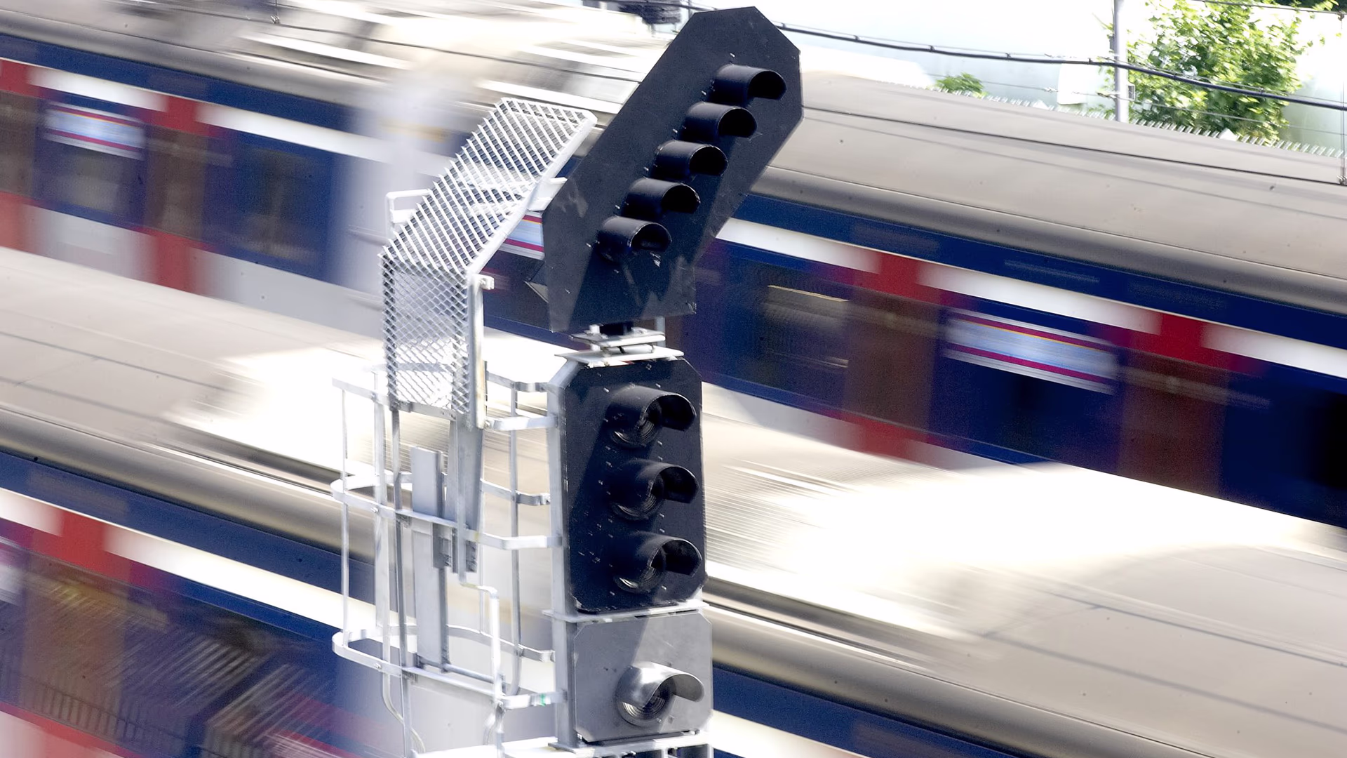 vorbeirassender Zug und ein Signal Siemens Mobilty Signaltechnik