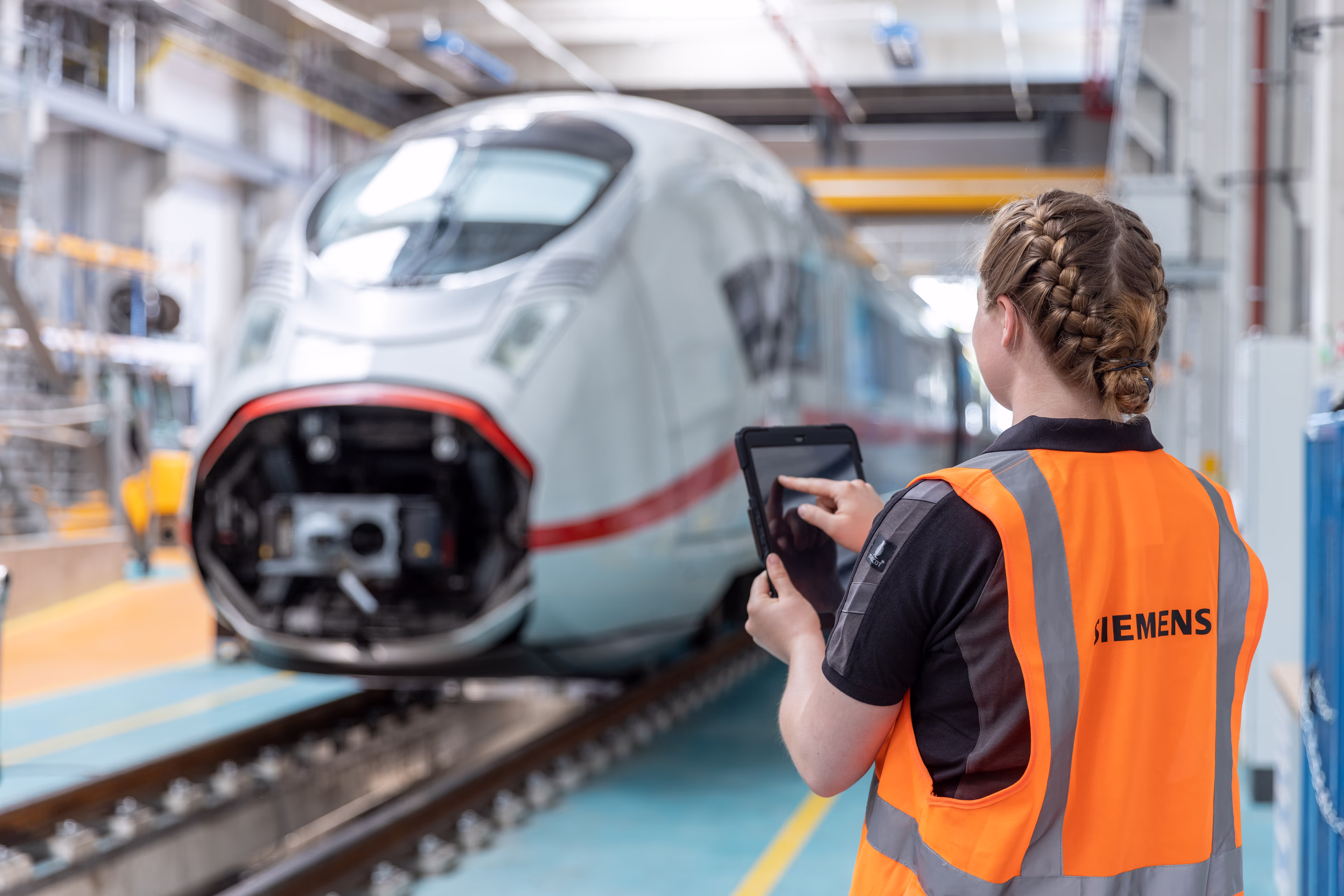 A young female technician is working on her tablet in a Siemens Service Center velaro-technician-tablet