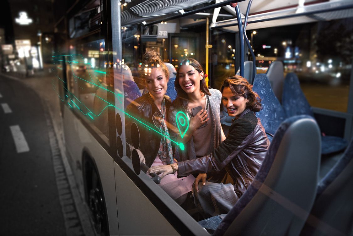 Three women sitting in a bus, using MaaS app for intermodal mobility on demand