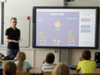 Teacher presenting educational game on large screen to students