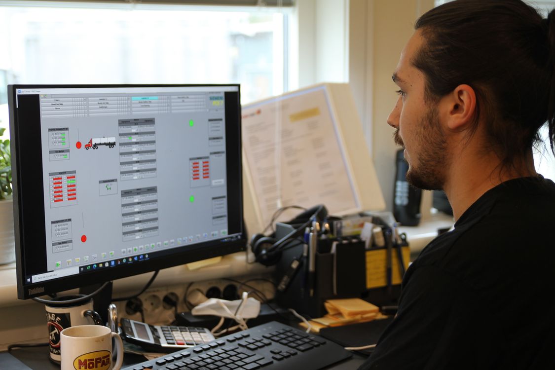 I driftrummet kan OKQ8:s drifttekniker, här Adrian Stenberg, enkelt felsöka och se diagnostik från givare, ventiler och pumpar i realtid. Lösningen är baserad på en standardiserad och integrerad systemplattform med Simatic PCS 7, Comos, Simit och Opcenter Execution och inkluderar recepthantering, modulär uppbyggnad för framtida förändringar, tydlig larmhantering, smidig åtkomst till data via rapporter samt full kontroll på flöden och lastade produkter.
