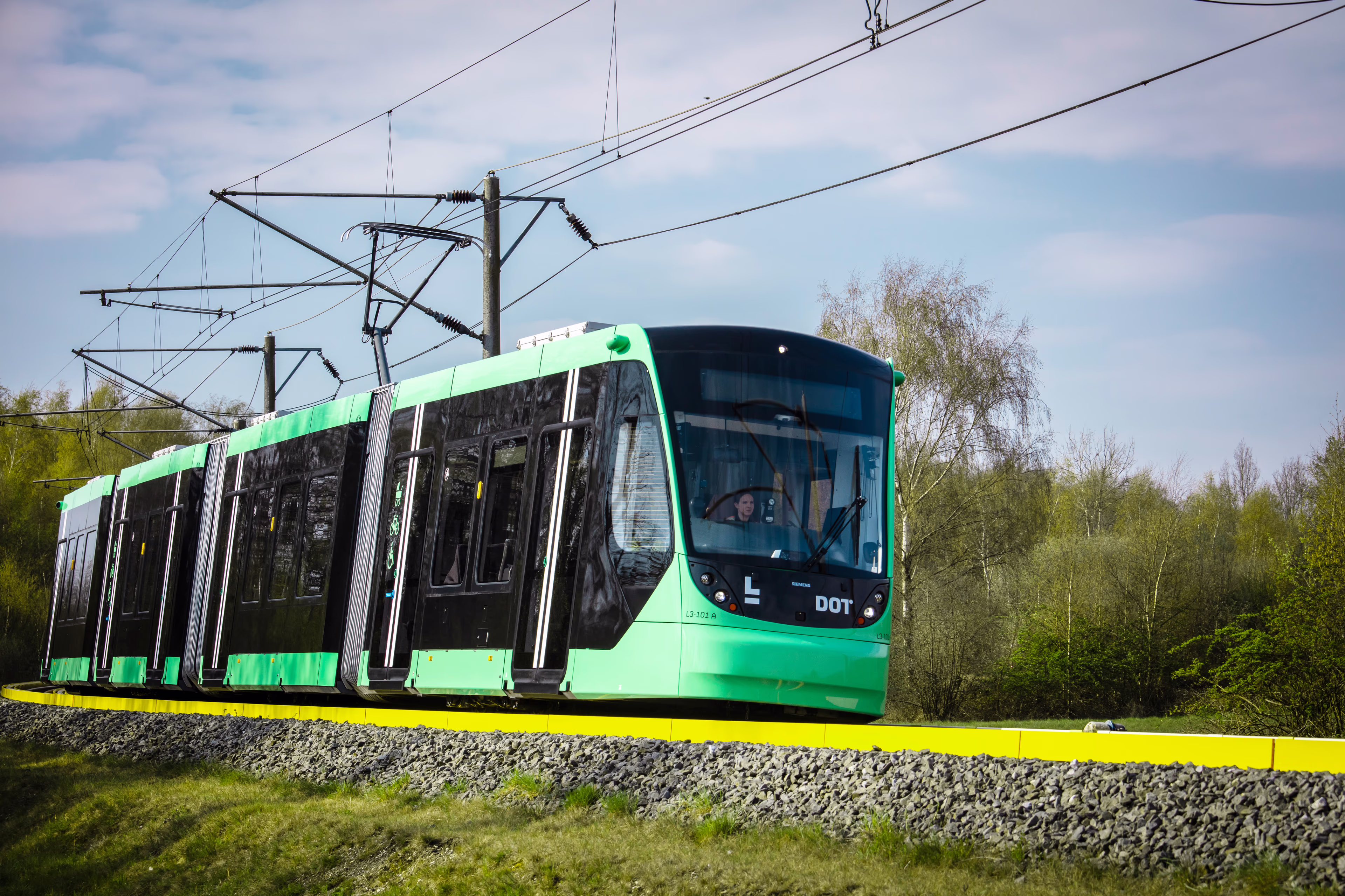 Grønt letbane tog set i grønt landskab Avenio tog til Københavns letbane