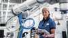 Servicetechnikerin vor Industrieanlage mit Notizblock und in die Kamera blickt Servicetechnikerin vor Industrieanlage mit Notizblock und in die Kamera blickt