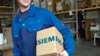 Customer Service Techniker hält eine Kartonkiste mit dem Schriftzug Siemens unter dem Arm
