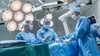 Surgeons in scrubs and masks in operating room environment performing a surgery