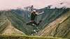 tjej hoppar glatt vid en grönskande bergstopp