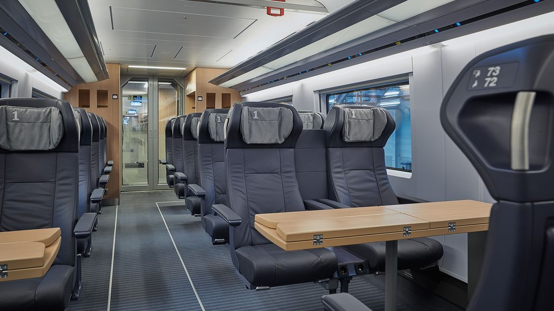An interior view of the Velaro MS showing the seats, some of which are in a face-to-face arrangement with tables.