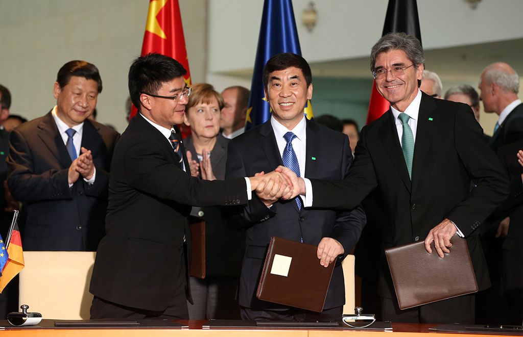 Chinese President Xi Jinping (background L) and German Chancellor Angela Merkel (background R) look on as Siemens AG CEO Joe Kaeser (R) shakes hands with Huang Dinan(L), Vice-Chairman of Shanghai Electric Group Co., Ltd. and Cao Peixi (M), Chairman of Huaneng Power International Inc. during the signing of a Memorandum of Understanding in Berlin on March 28, 2014.