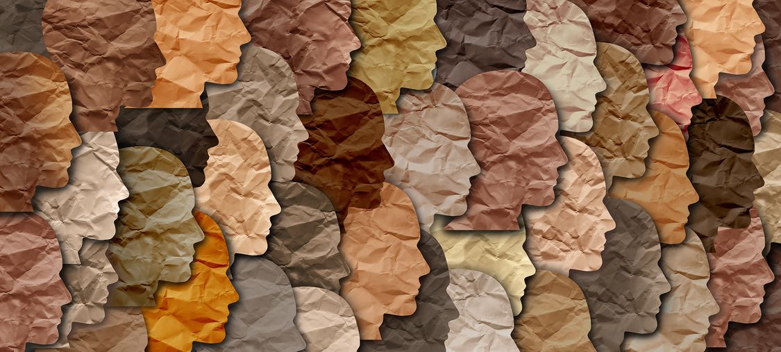Illustration showing many faces in profile, made of paper and representing different skin colors 