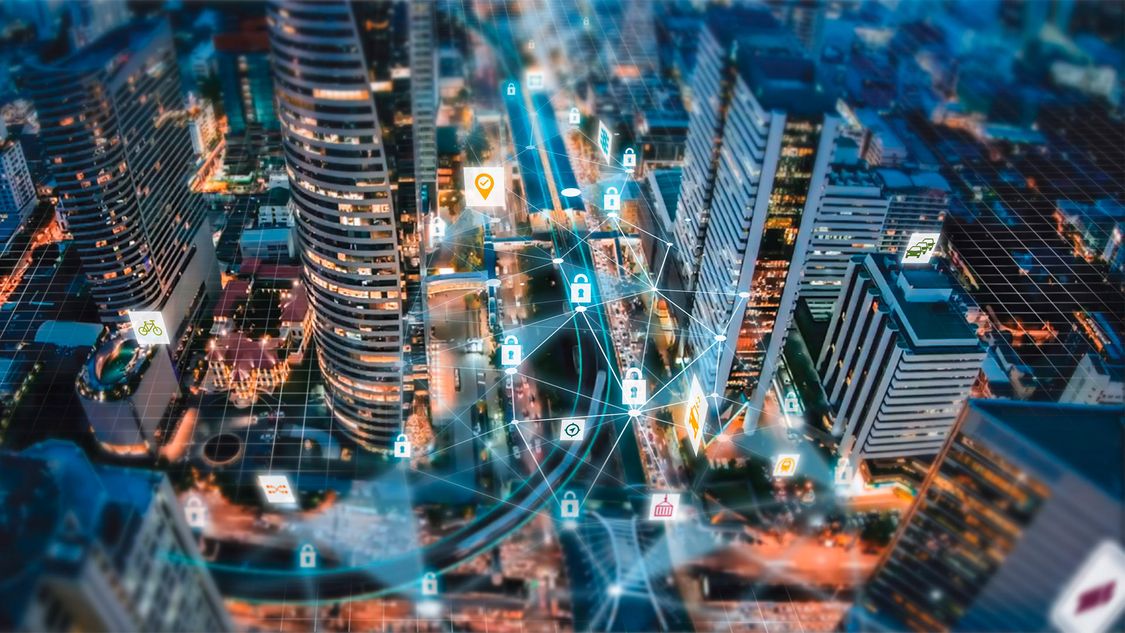 An aerial view of a city at night is overlaid with connected icons representing cybersecurity in mobility