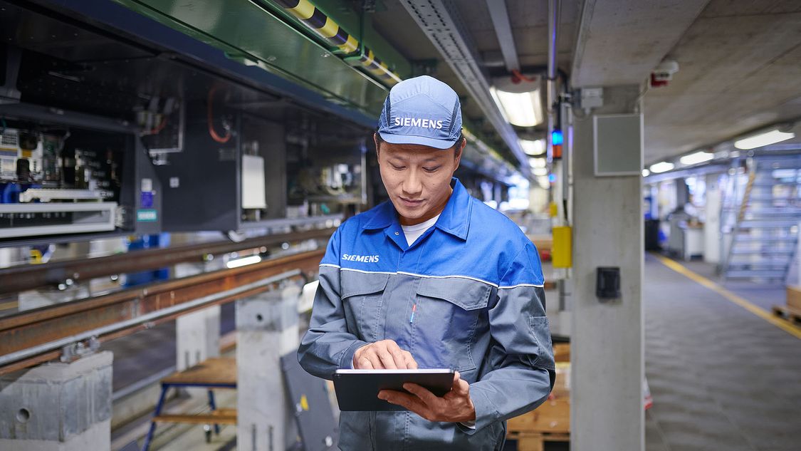 A Siemens Mobility service employee looks at his tablet maintaining a metro in Bangkok.