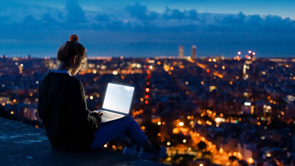 Woman working on a laptop in front of a city skyline