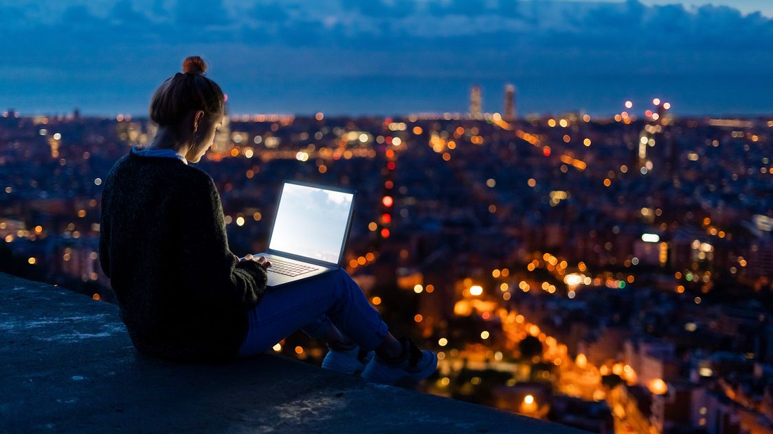 women looking at her laptop and city at night