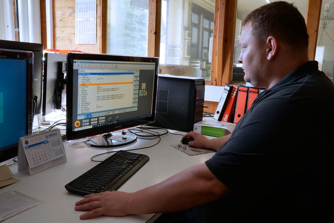 Photo of a CNC operator at his desk at a PC showing the SinuTrain software.